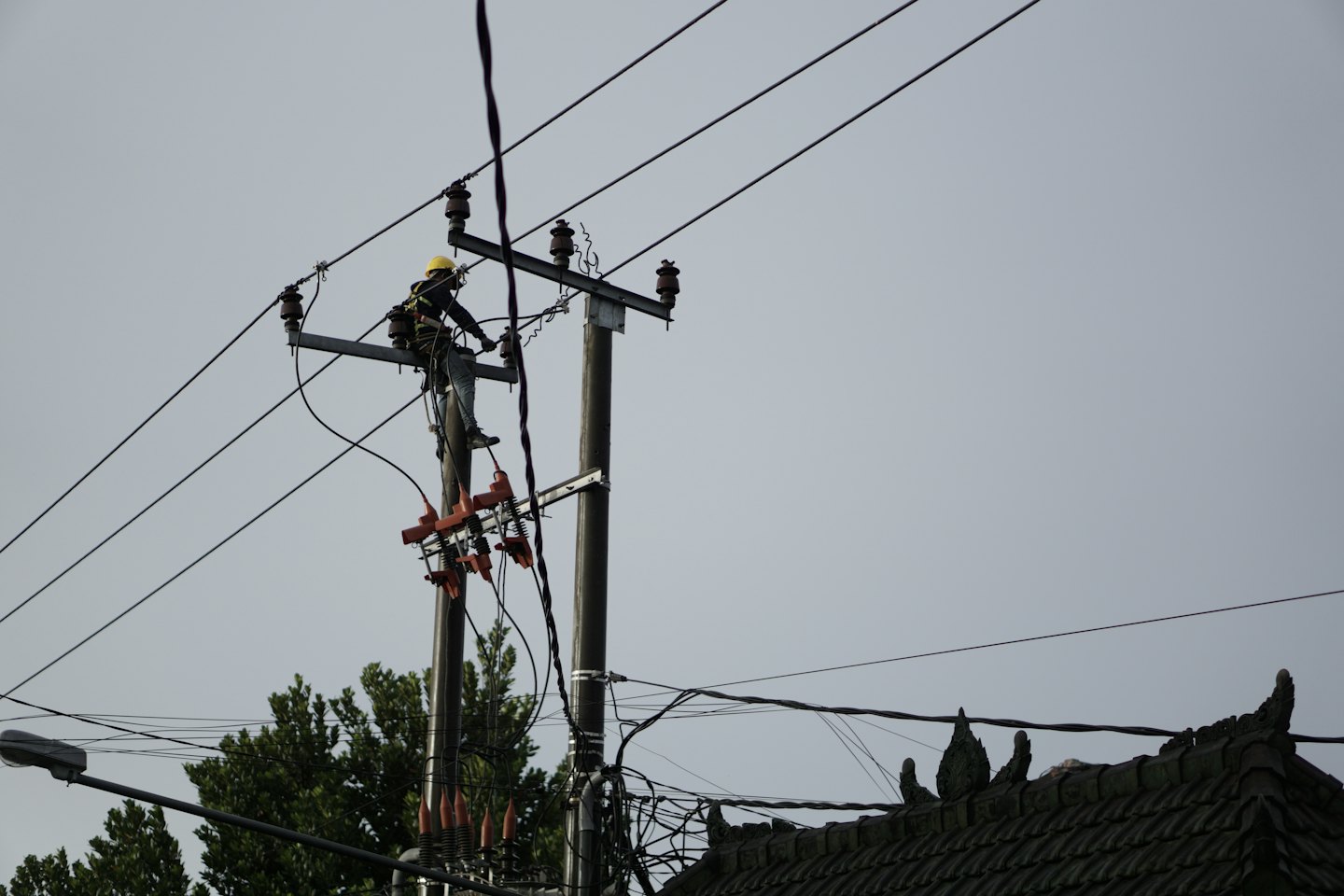 Un electricista en un poste de servicios públicos trabaja en cables.